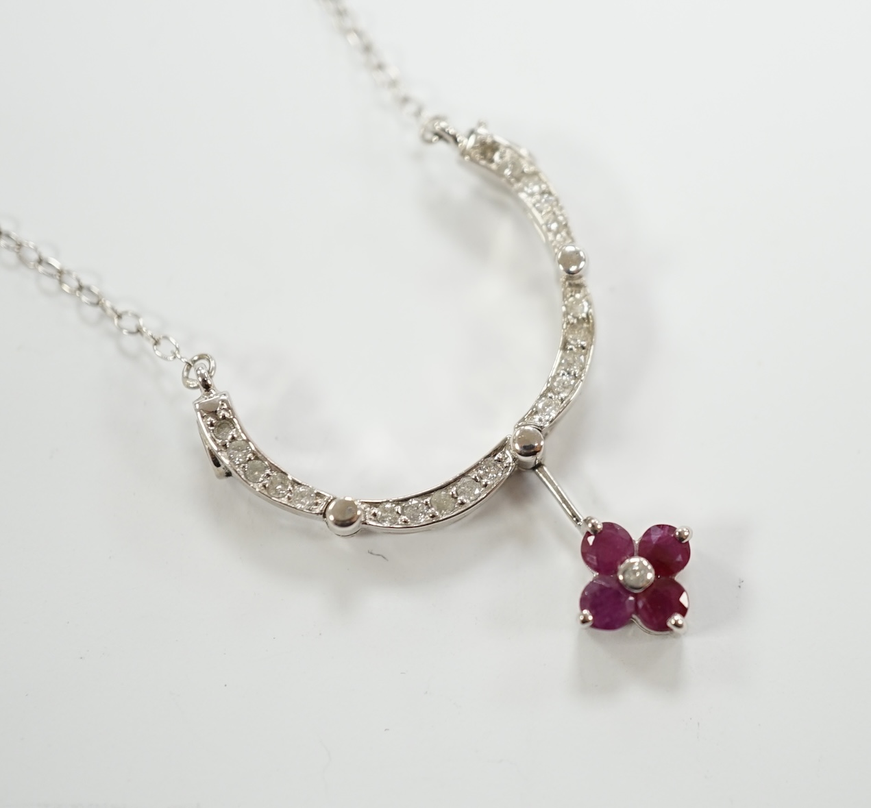 A modern 14ct white gold, ruby and diamond cluster set metamorphic pendant, 21mm, on a 14k white metal fine link chain, 38cm, gross weight 3.8 grams.